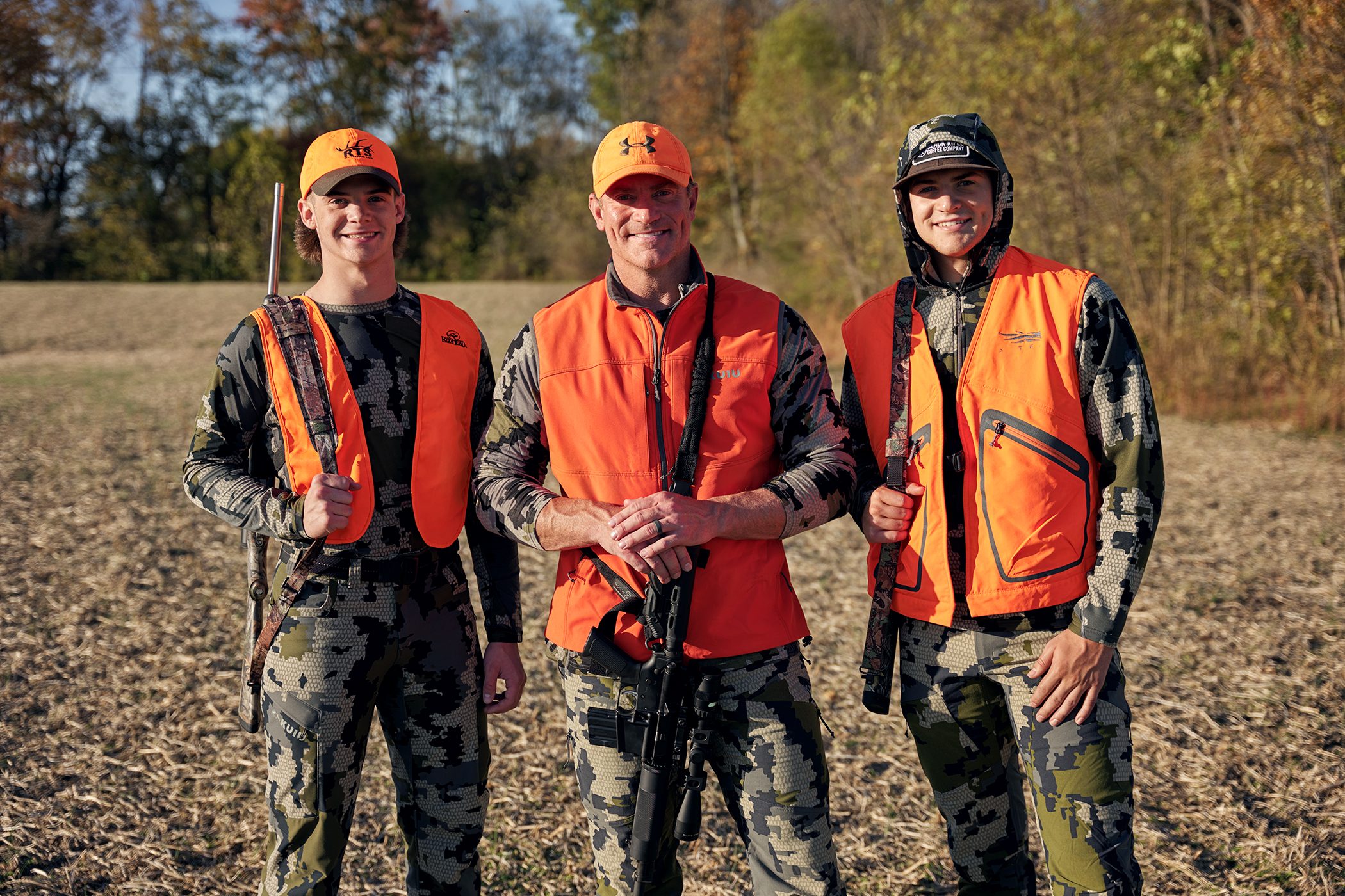 Chris Garten hunting outdoors with two young men in blaze-orange vests