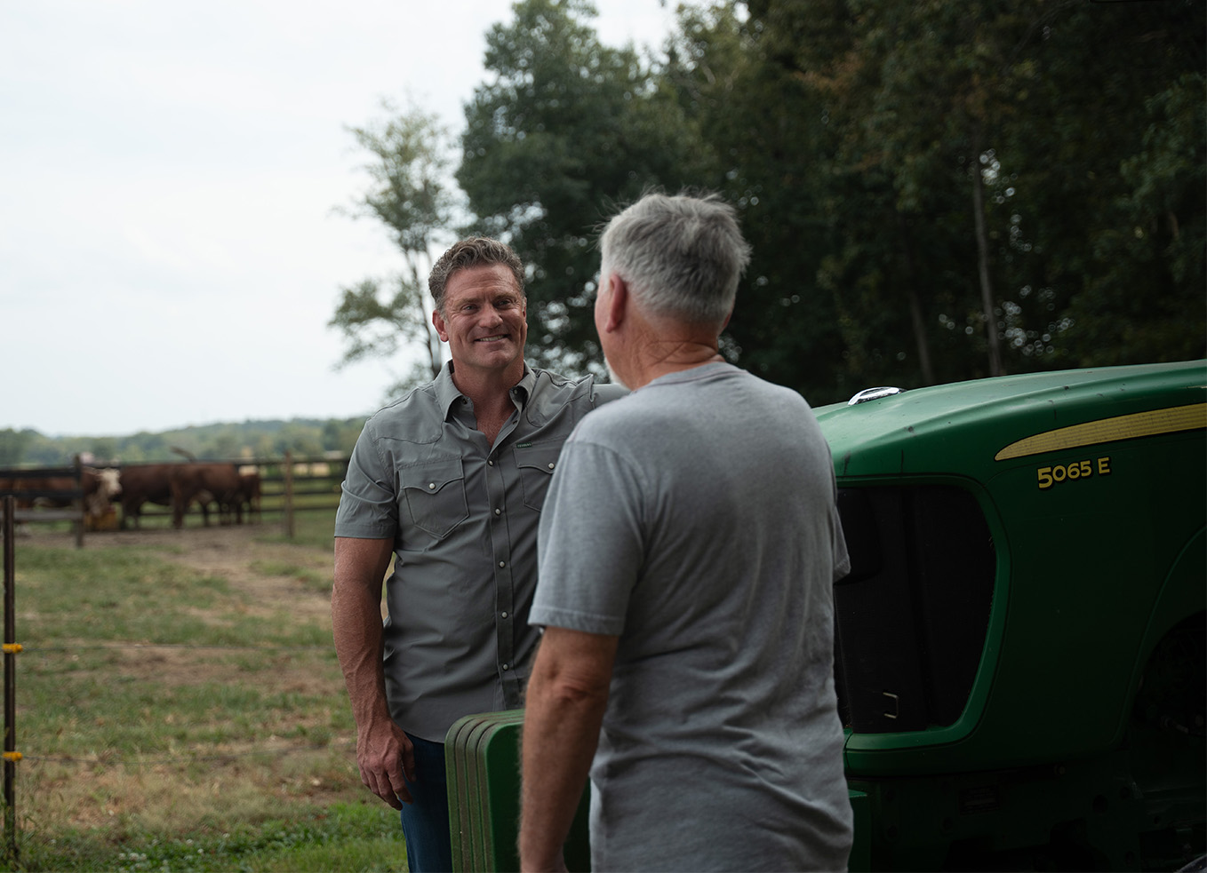 Chris Garten talking with a man beside a green tractor