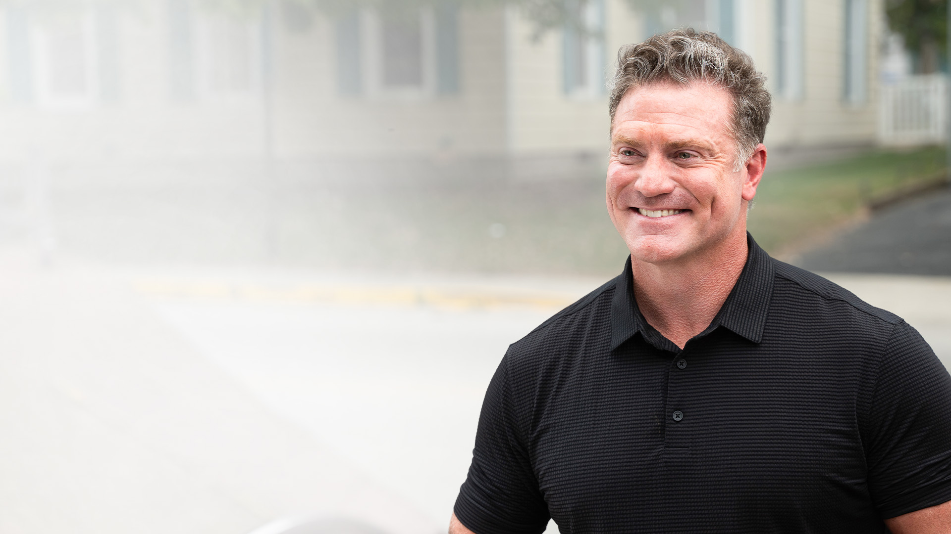 Chris Garten smiling outdoors in a black polo shirt